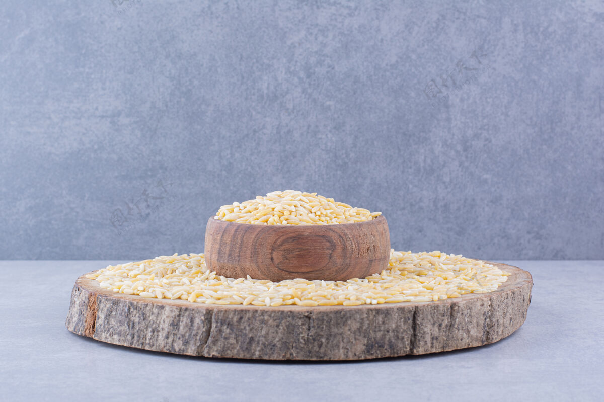 碗Brownrice在一块圆木上堆满了一个圆木 中间有一个满满的碗 在大理石表面健康谷物饮食