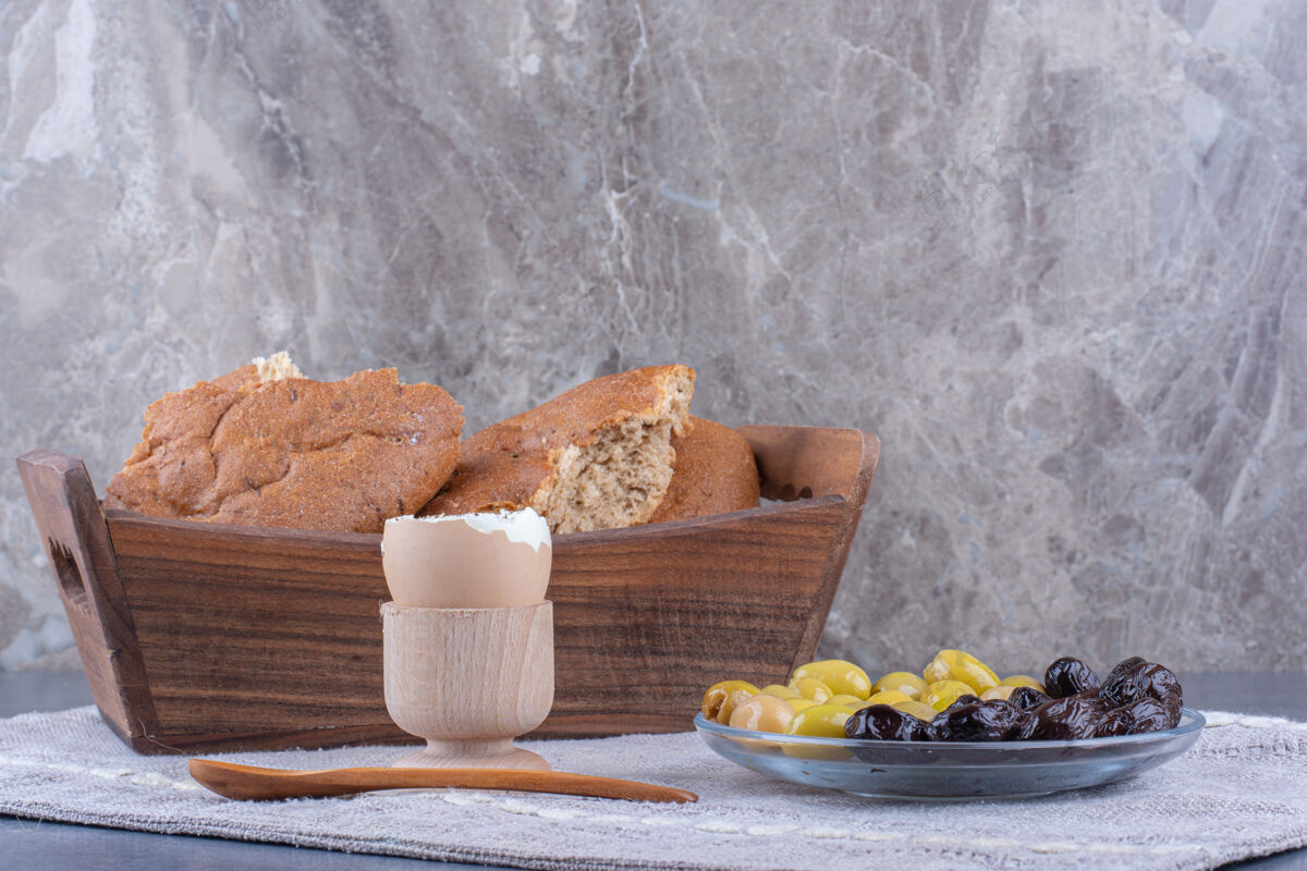 勺子简单的早餐 面包 鸡蛋和橄榄放在大理石表面橄榄早餐饮食