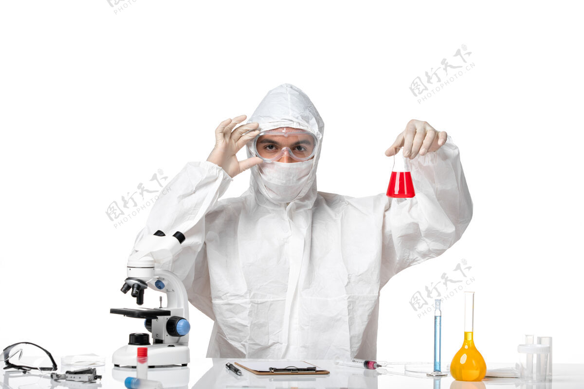 人正面图：男医生穿着防护服 戴着面罩 因为白色空间上有一个装有红色溶液的瓶子溶液医学专业
