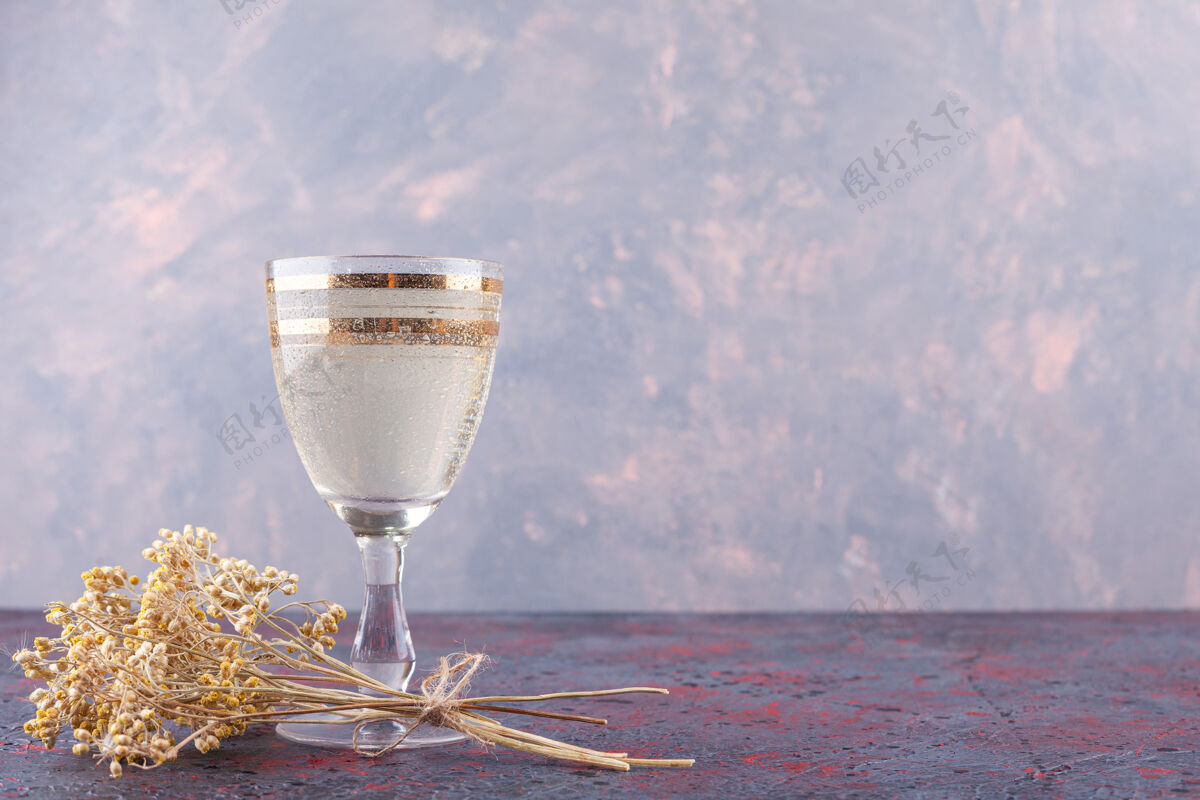 潮湿一杯带有干花的矿泉水放在深色的背景上冷杯子纯净