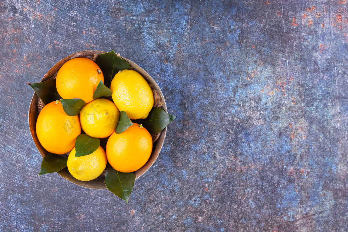 热带装满新鲜柠檬的金属碗 大理石背景上有叶子生的新鲜果汁