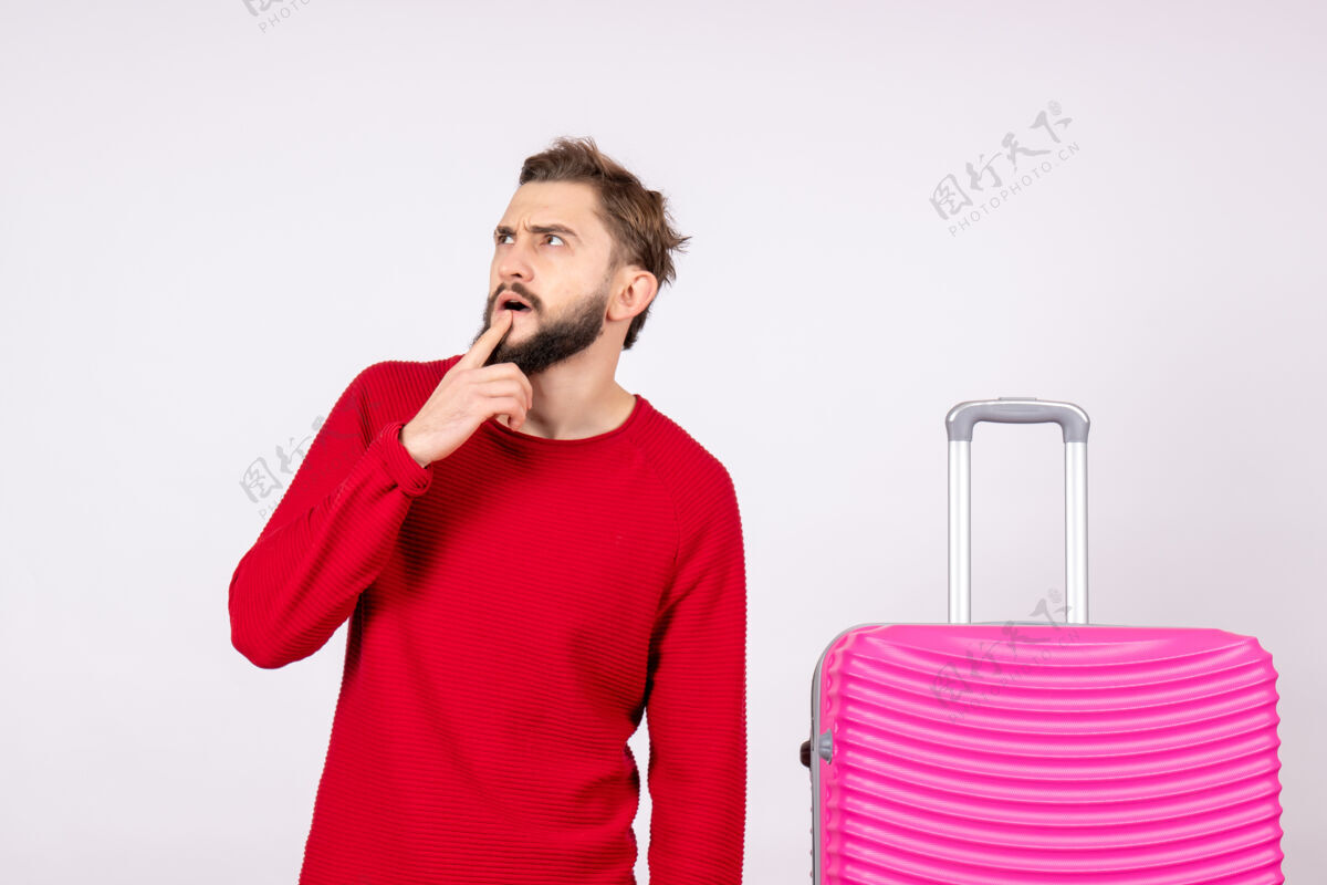 颜色正面图白色墙壁上带着粉色包的年轻男性旅行照人色度假飞行远航飞行耳机肖像