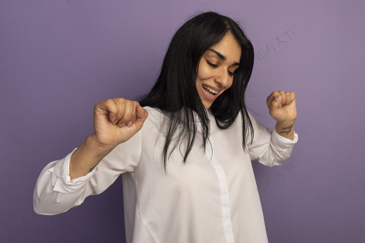 穿上微笑的年轻漂亮女孩穿着白色t恤在紫色上跳舞紫色跳舞年轻