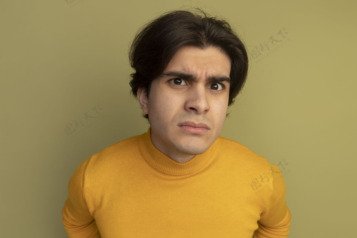 可疑可疑的年轻帅哥穿着黄色高领毛衣孤立在橄榄绿的墙上高领毛衣奥利弗年轻