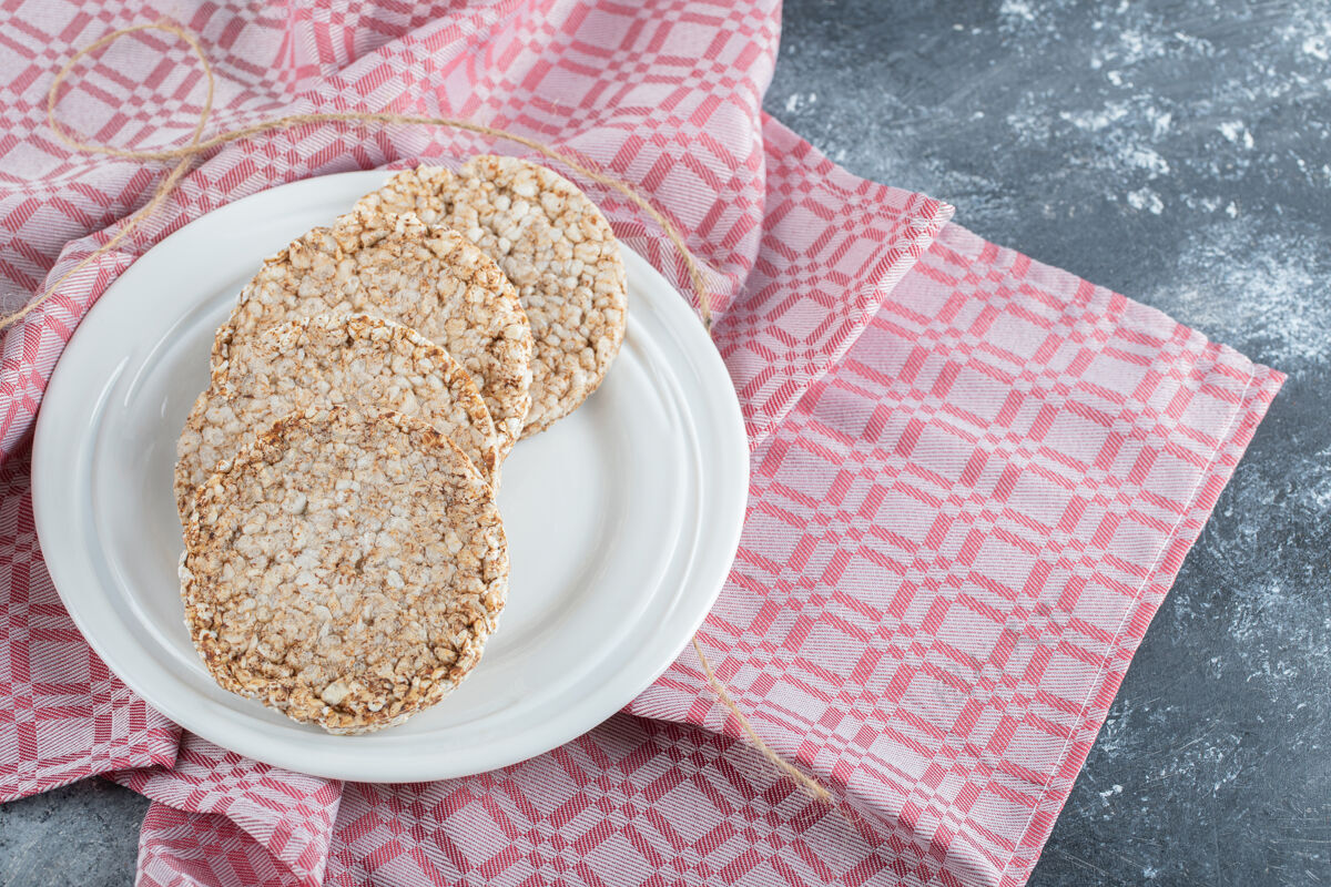 谷类食品在桌布上放满了膨化米饭面包的白色盘子米饭小吃饼干