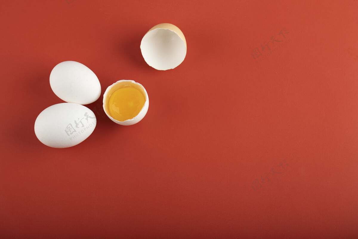 生红色表面上的碎鸡蛋和整个生鸡蛋烹饪鸡蛋禽类