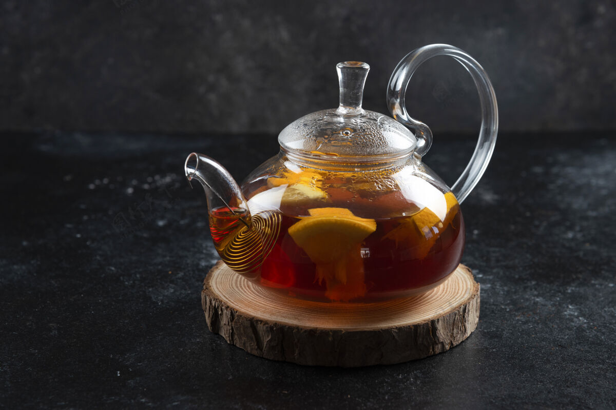 罐子一个有热茶和柠檬片的玻璃茶壶草药鸡尾酒冷