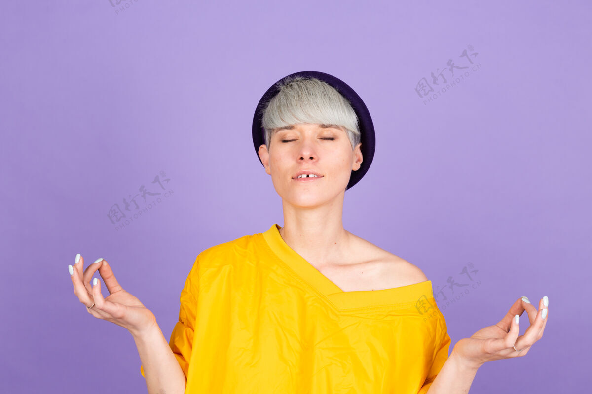 位置紫色墙上的时髦欧洲女人放松 微笑着用手指做冥想姿势冷静手势瑜伽