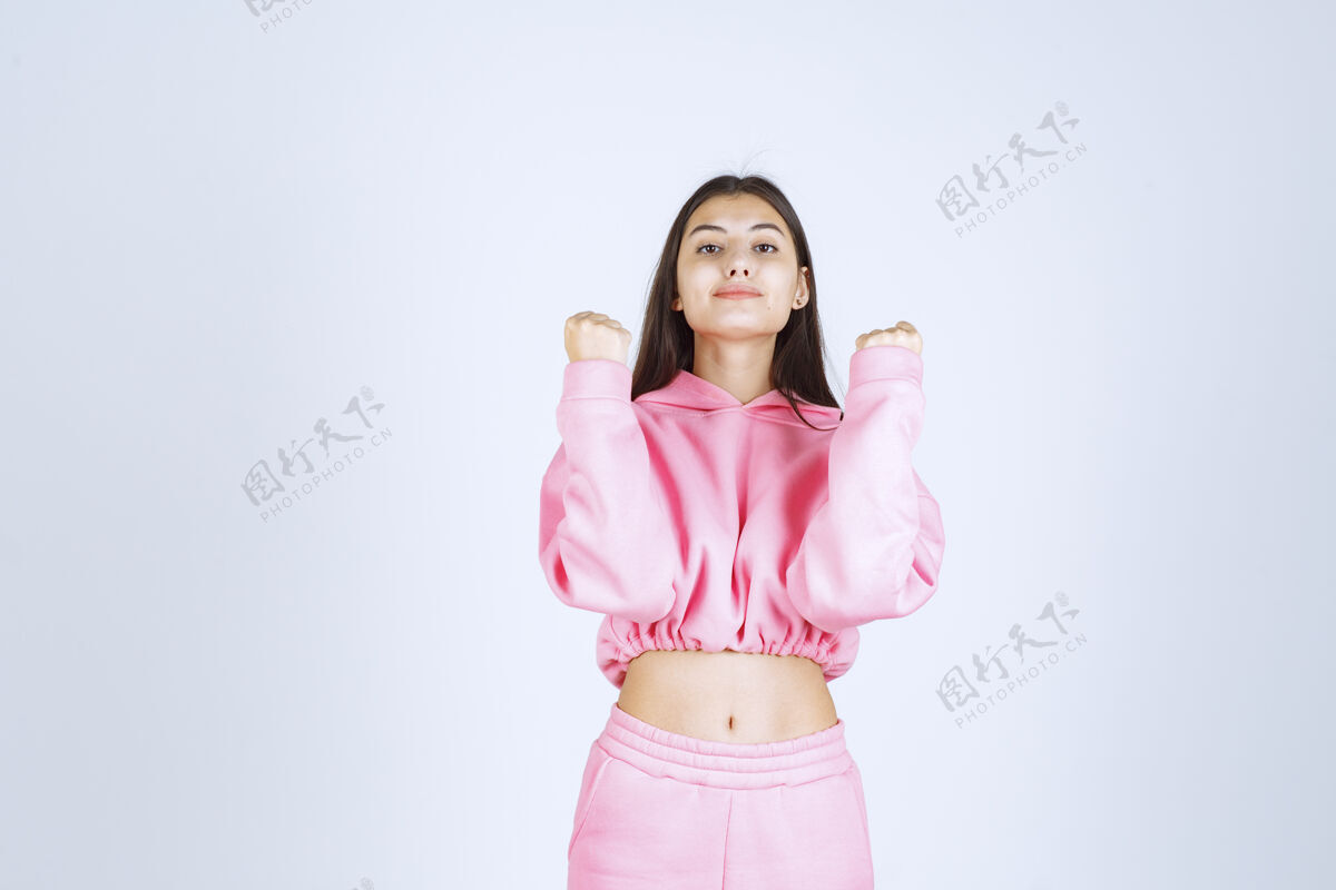 人穿粉红色睡衣的女孩看起来很有运动气息 还伸出拳头休闲成人女人
