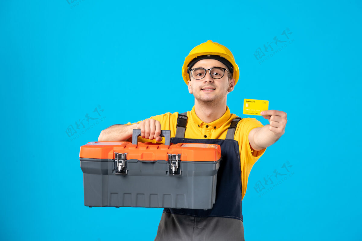 服务前视图男工人穿着制服 头盔工具箱和银行卡在蓝色盒子工作银行