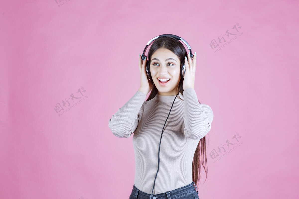 女人戴着耳机的女孩听着音乐 感觉很开心休闲微笑表演