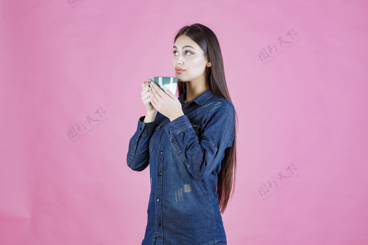 温暖女孩拿着一个白绿色的咖啡杯 闻着商业美食人类