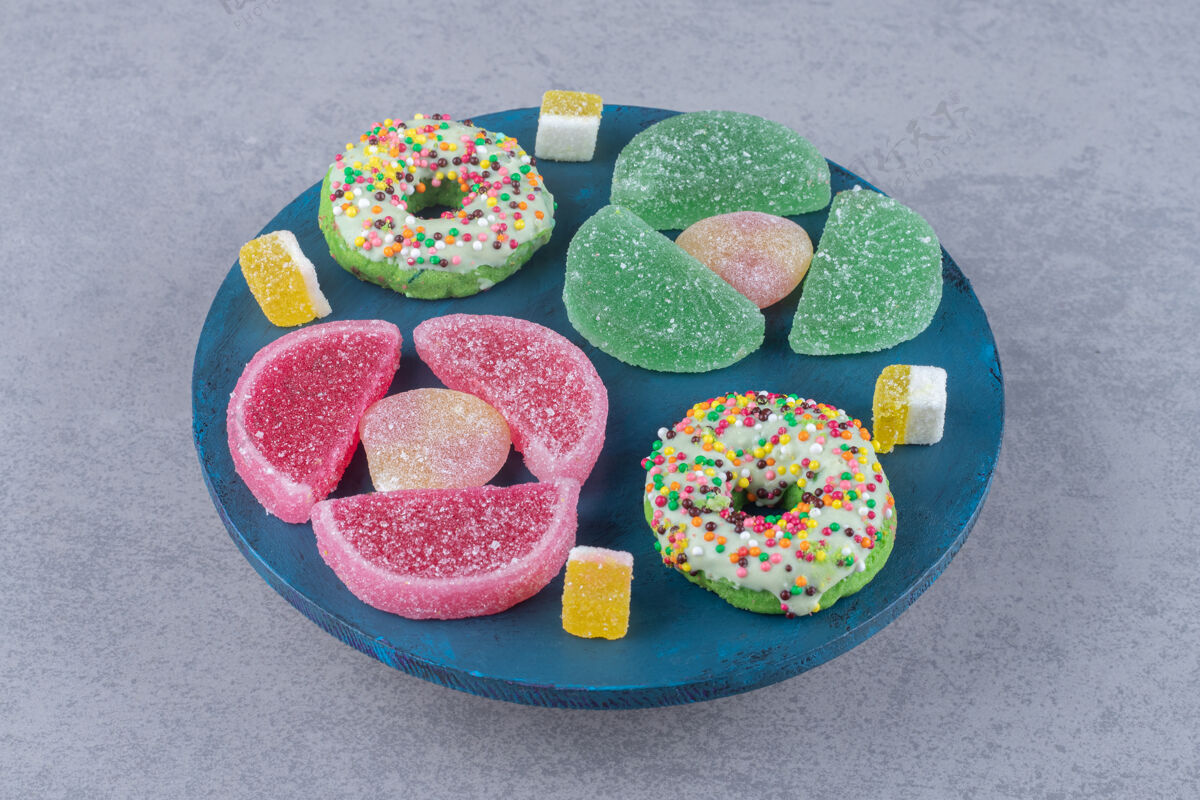 甜点在大理石表面的蓝色木板上放着一捆果酱和甜甜圈甜点糖果美味