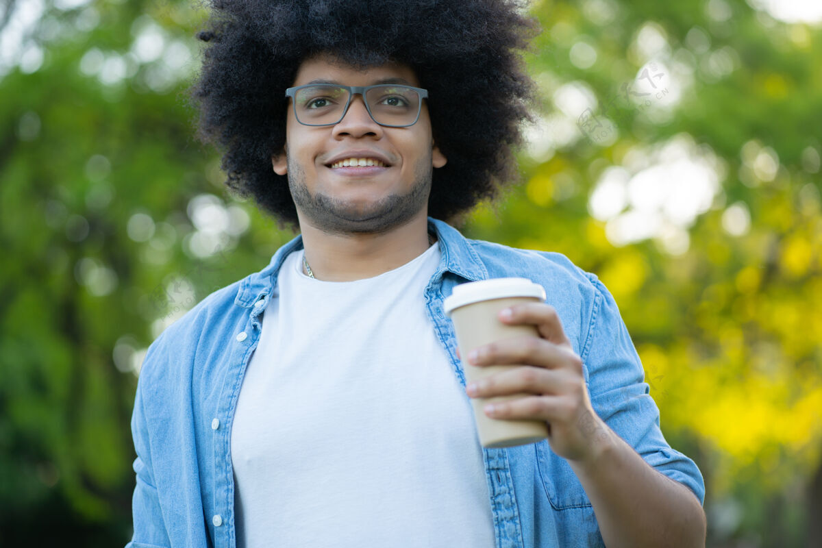 特写年轻的拉丁男子拿着一杯咖啡在街上走在户外的肖像咖啡杯杯子人