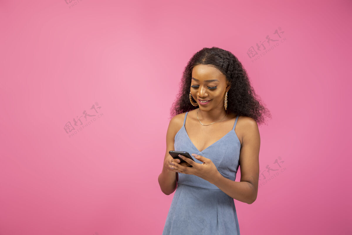 社交媒体特写镜头中的一个美丽的非洲裔美国女孩在一个激动人心的心情举行她的手机抱着电话年轻