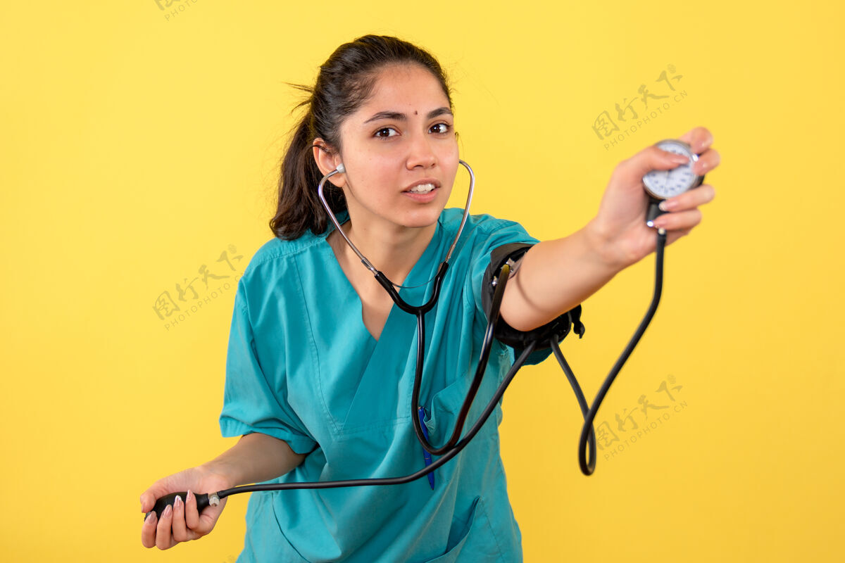 诊所前视图女医生穿着制服使用血压测量仪护理测量人