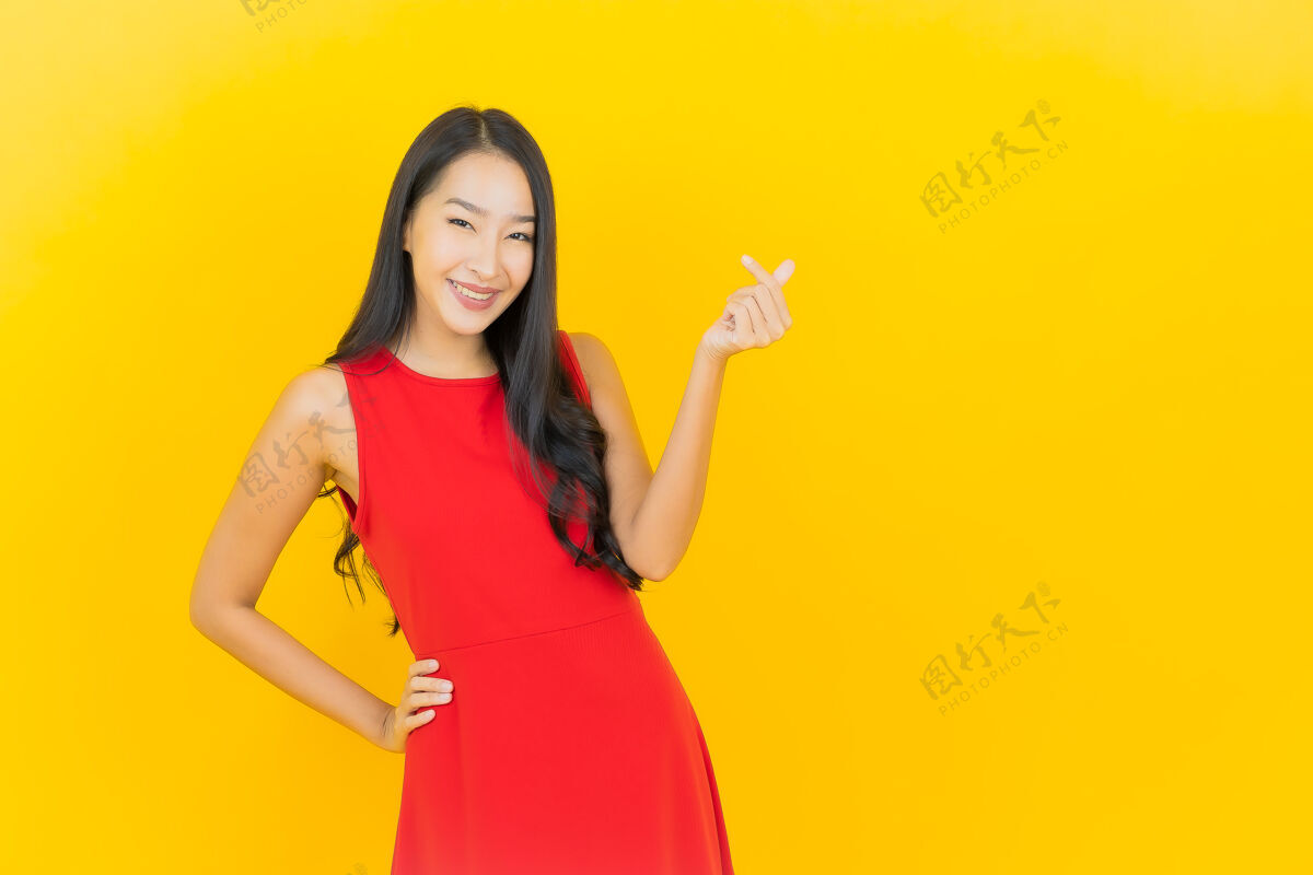 女人肖像美丽的亚洲年轻女子穿着红色连衣裙微笑着行动在黄色的墙上紫色亚洲人女人