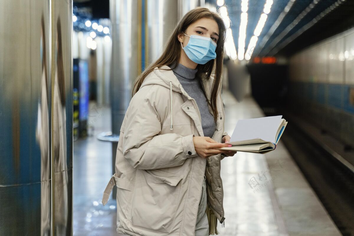 外科口罩在地铁站看书的年轻女子地铁大都会感冒