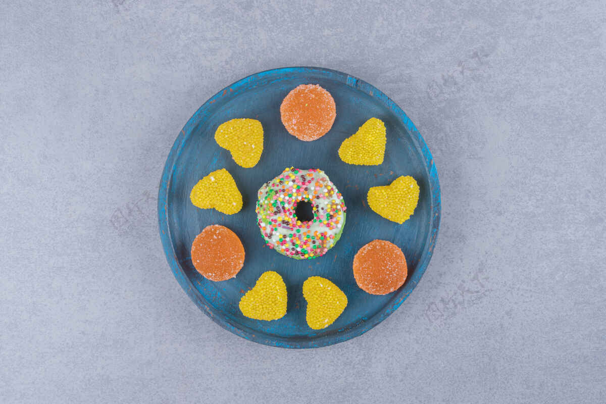 烘焙食品蓝色的盘子和一个小甜甜圈和各种大理石表面的marmelades`甜点小吃拼盘