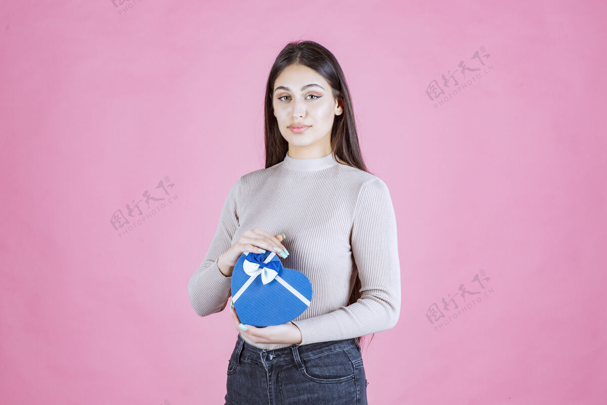 热情拿着一个蓝色心形礼品盒的女孩在演示姿势成人惊喜