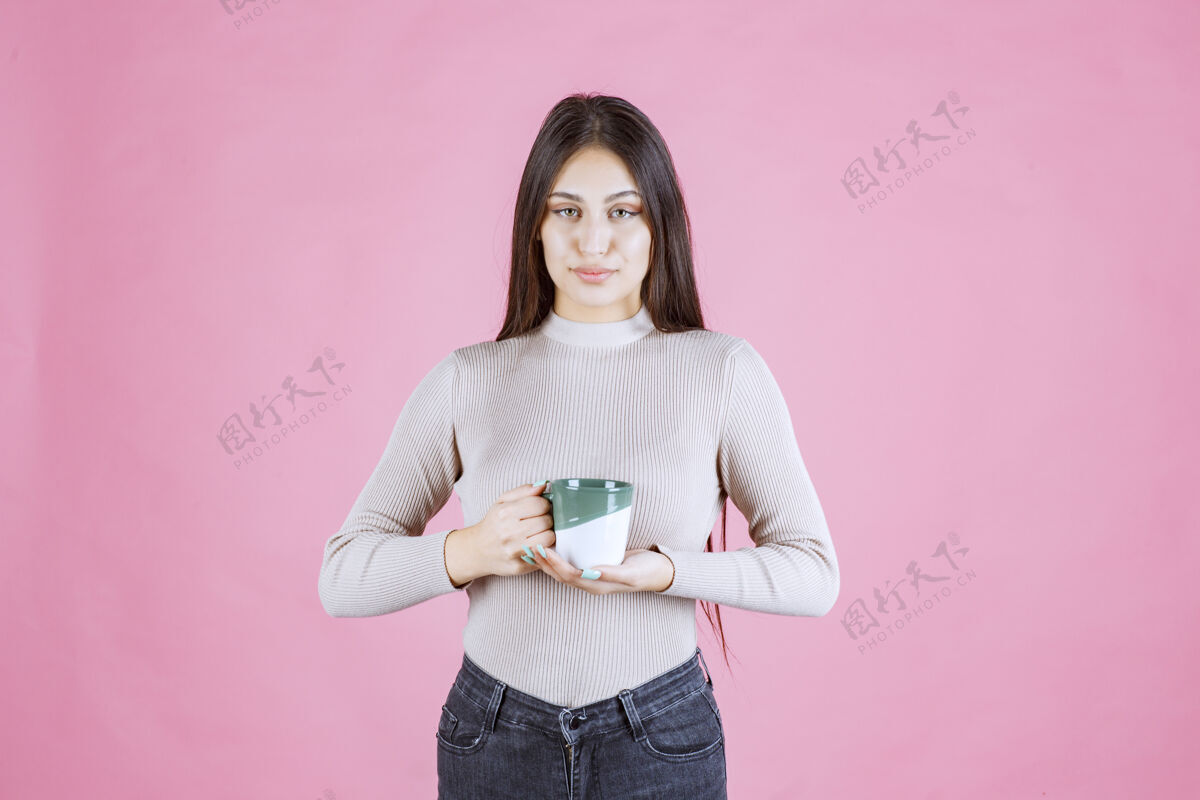人女孩拿着一个白绿色的咖啡杯 感觉很积极温暖热杯子