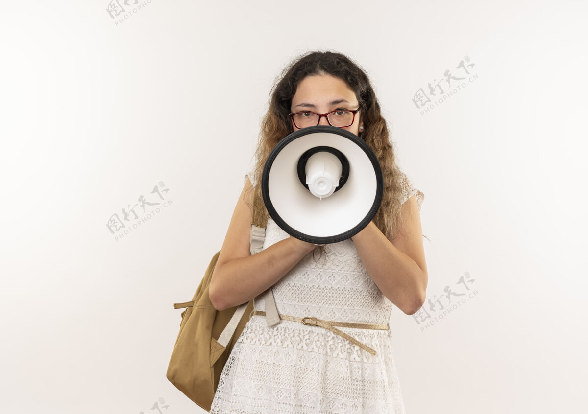 年轻年轻漂亮的女学生戴着眼镜 背着书包说话 演讲者看着隔离在白色背景和复印空间的相机包漂亮穿