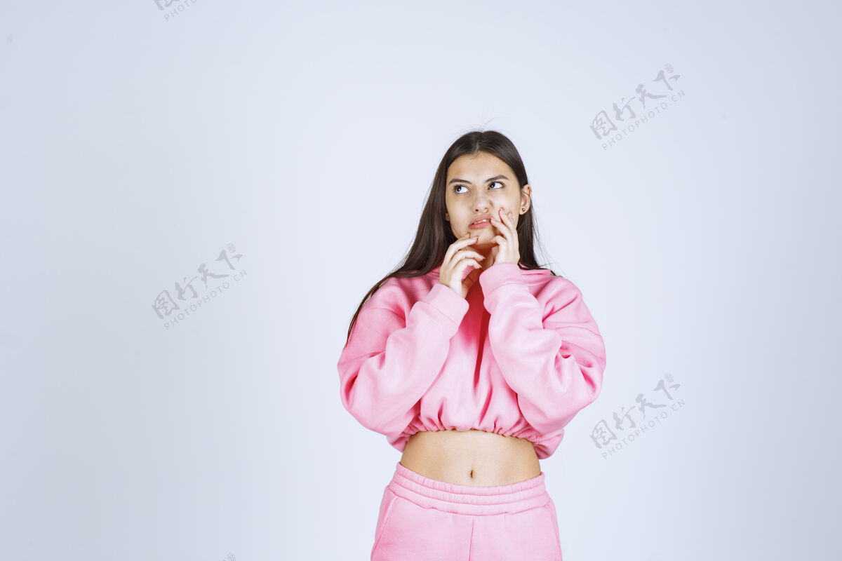 女性穿粉红色睡衣的女孩看起来既困惑又怀疑成人虽然人