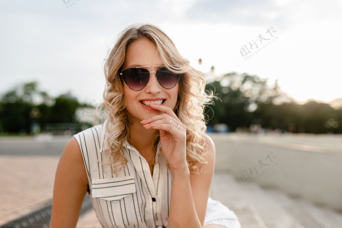 脸城市街道上一位年轻迷人的时尚金发女郎的特写肖像 穿着夏季时尚的连衣裙 戴着太阳镜女孩清新年轻