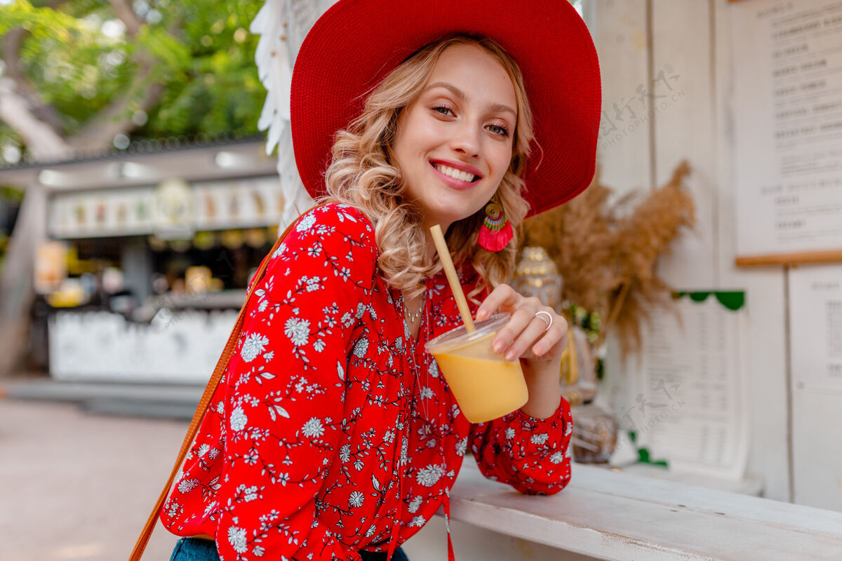明亮迷人时尚的金发微笑女士 头戴草帽 身穿短衫 夏季时尚套装 饮用天然水果鸡尾酒冰沙女人女士冰沙