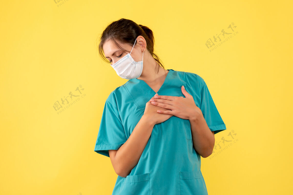 女医生前视图黄色背景上穿着医用衬衫和面罩的女医生一衬衫健康