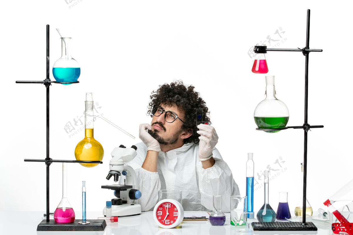 烧杯正面图身着特殊套装的年轻男科学家拿着样品在白墙上思考实验套装视图