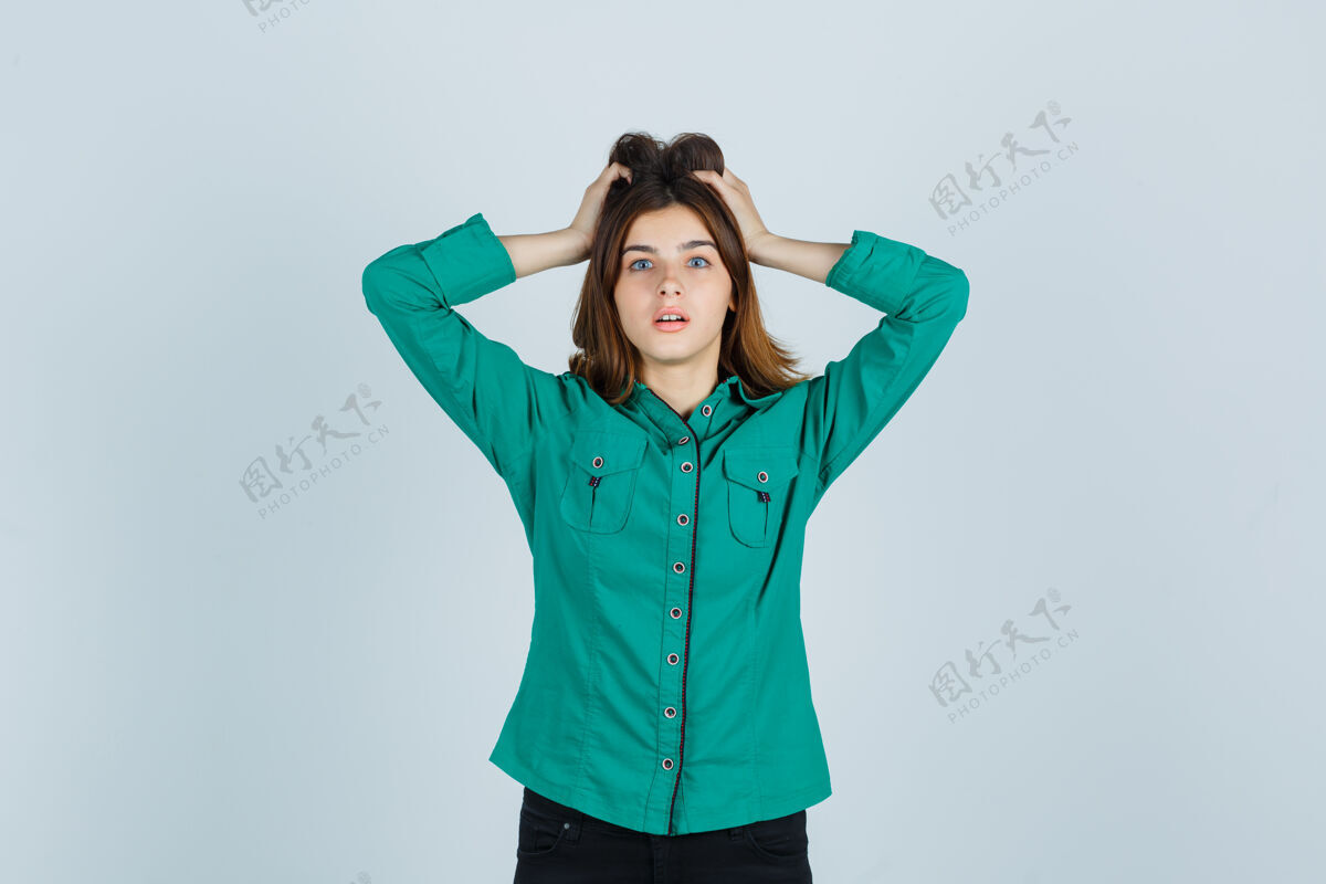 困惑穿绿衬衫的年轻女士手举在头上 神情茫然 俯视前方沉思手搜索