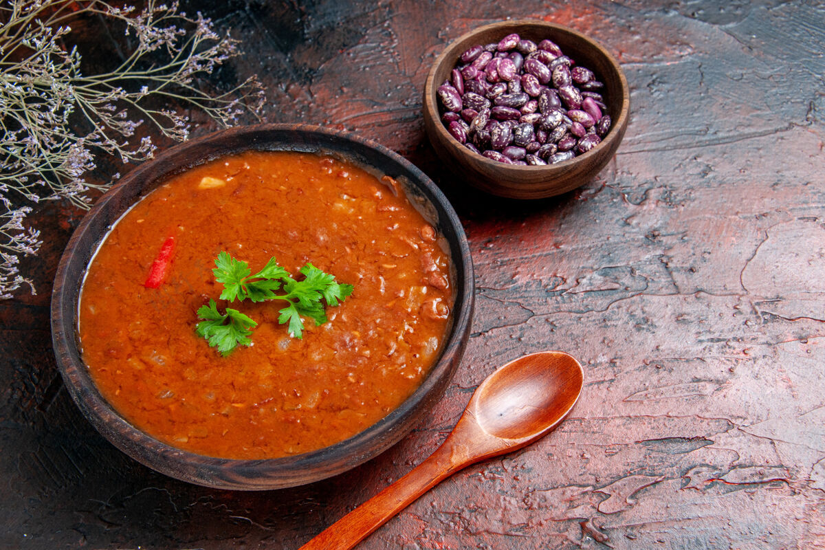 晚餐经典的番茄汤在一个棕色的碗里豆和勺子放在五颜六色的桌子上容器番茄汤午餐