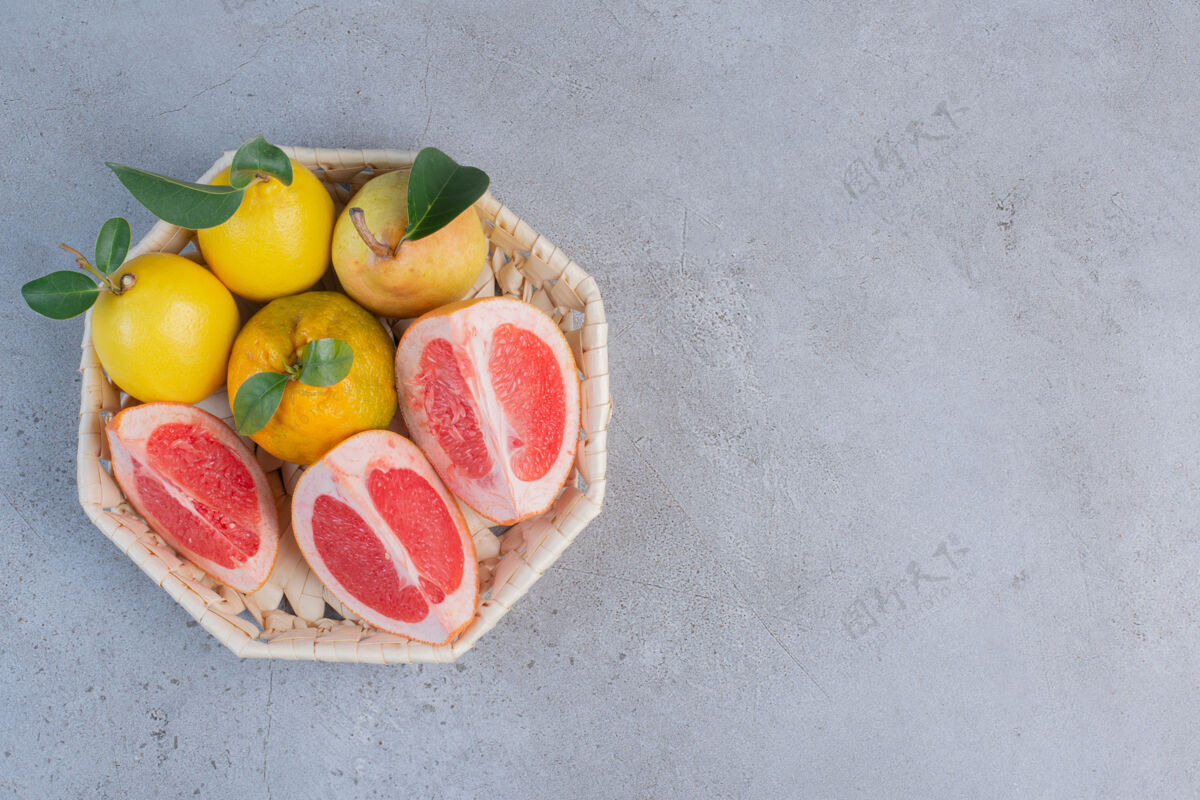 美味雪梨和葡萄柚片放在大理石背景上的白色篮子里配料美味美味
