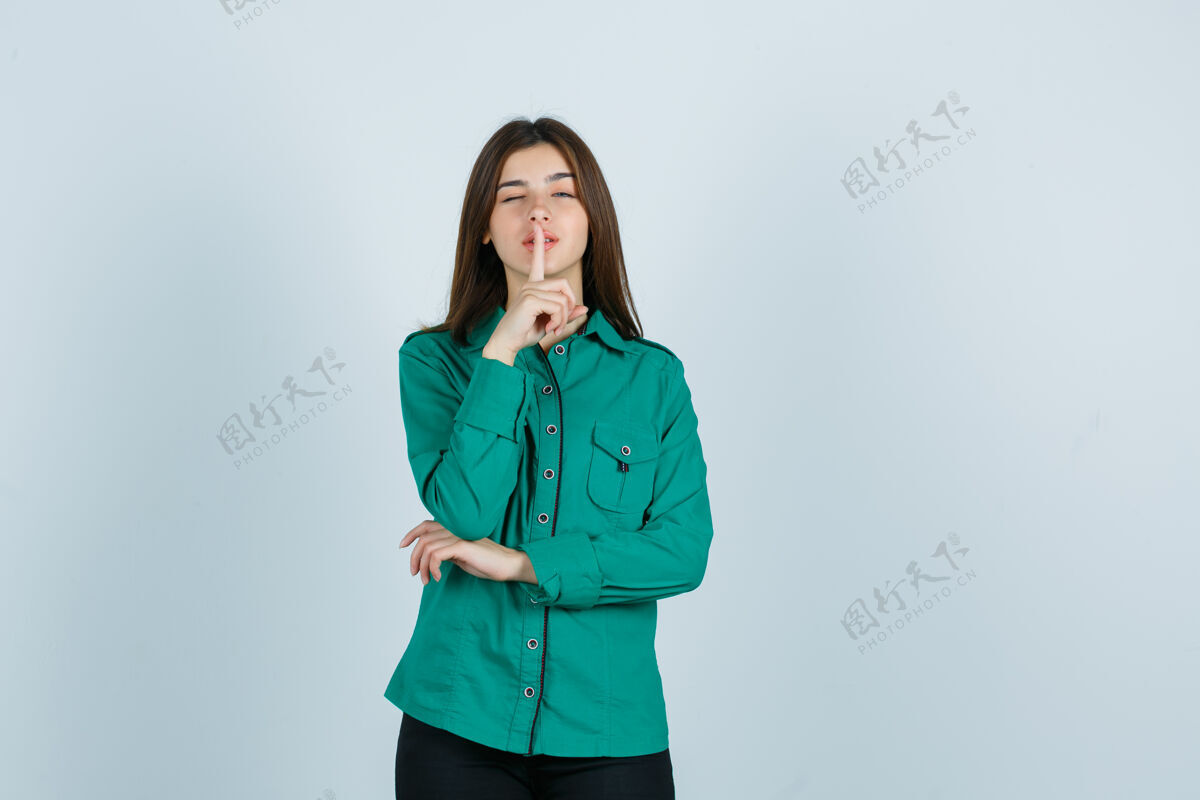 自信年轻的女性在展示沉默的姿态 同时在绿色衬衫闪烁 看起来很自信 正面视图姿势表演人物