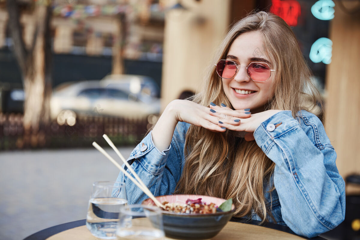 青年快乐微笑的女人在亚洲餐厅吃饭 看起来很傻休息脸城市