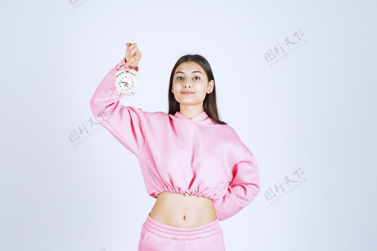 销售一个穿着粉色睡衣的女孩拿着一个闹钟 把它当作一个产品来推销工人雇员年轻