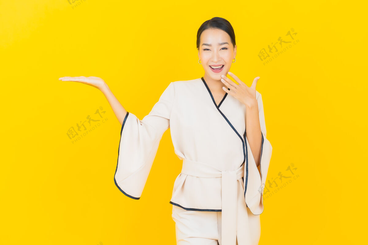 成功美丽的亚洲年轻商业女性在黄色墙上穿着白色西装微笑的画像正式西装美丽