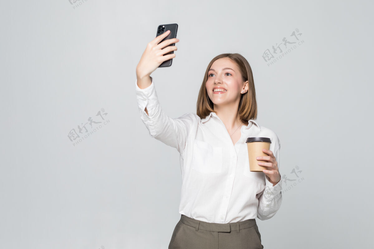 杯子身着正装的女商人手拿外卖咖啡站着用手机自拍的照片正式站立她自己