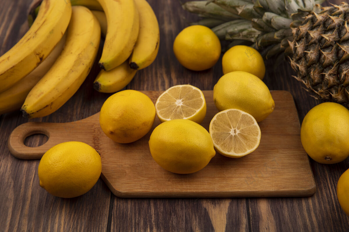 水果顶视图柑橘类水果一半和整个柠檬上的木制厨房板与菠萝和香蕉隔离在木制表面一半美味厨房