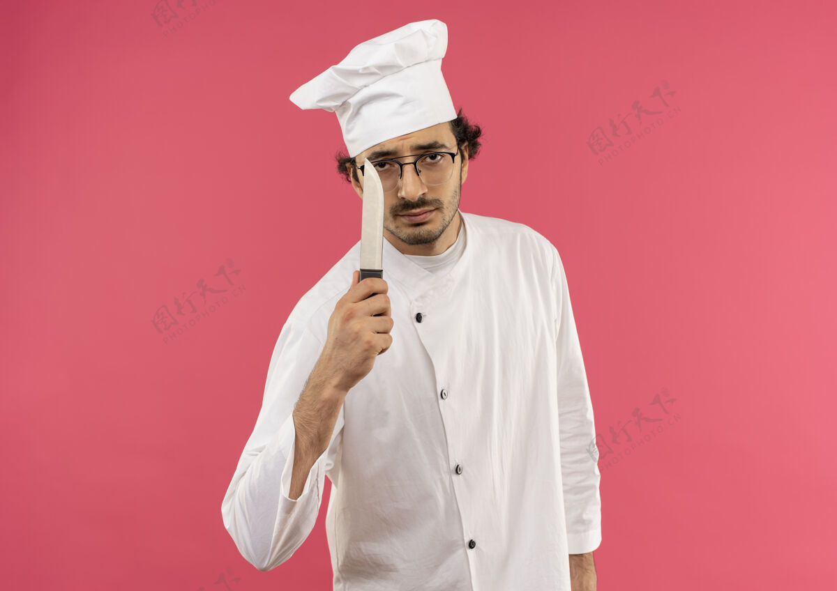 烹饪年轻的男厨师穿着厨师制服 戴着眼镜拿着刀男拿着厨师