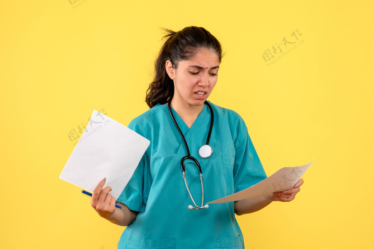 仪器前视图迷惑了站在黄色背景上的文件女医生球员医院高尔夫