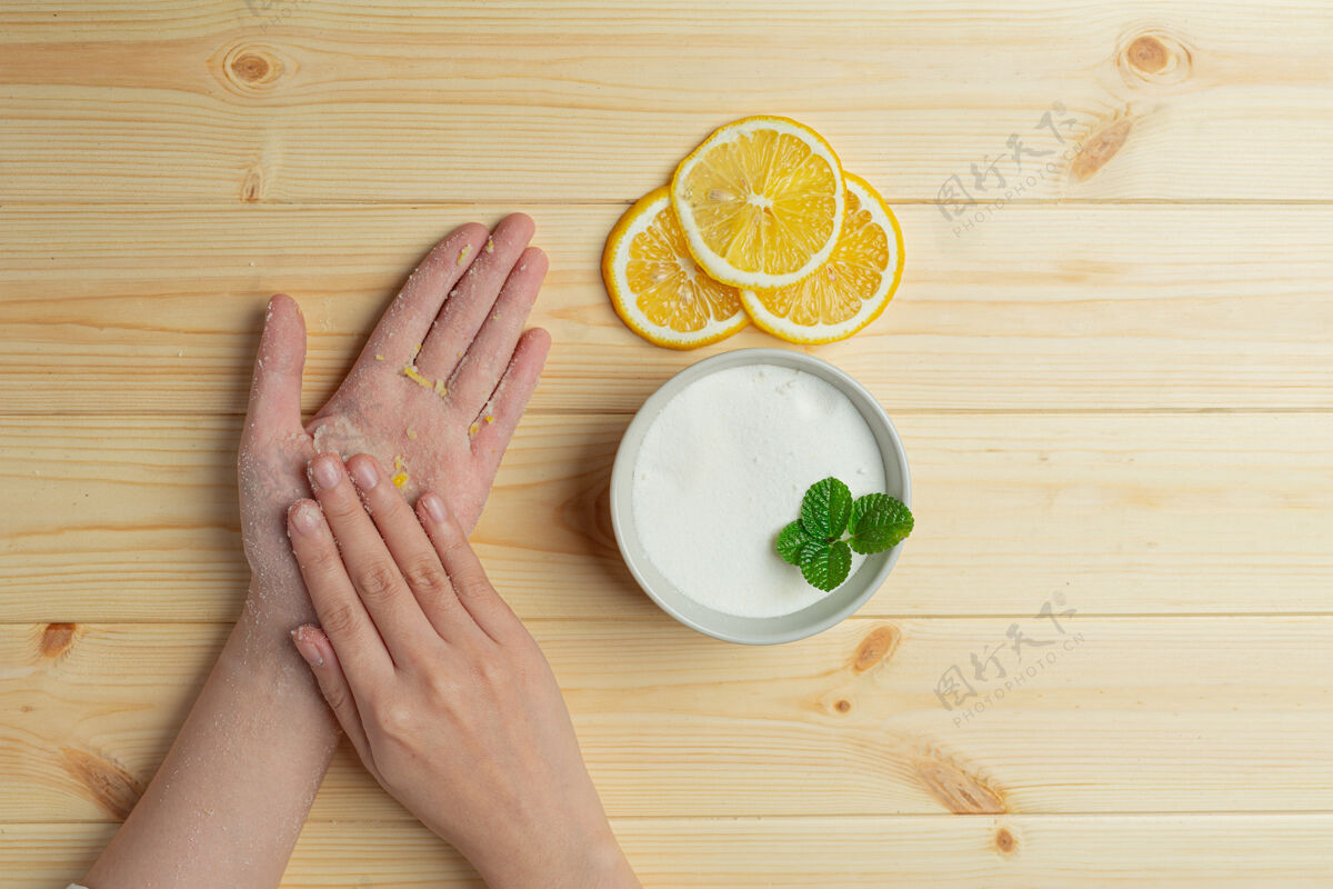 治疗年轻女子用天然柠檬磨砂膏擦在木桌上女性皮肤皮肤科