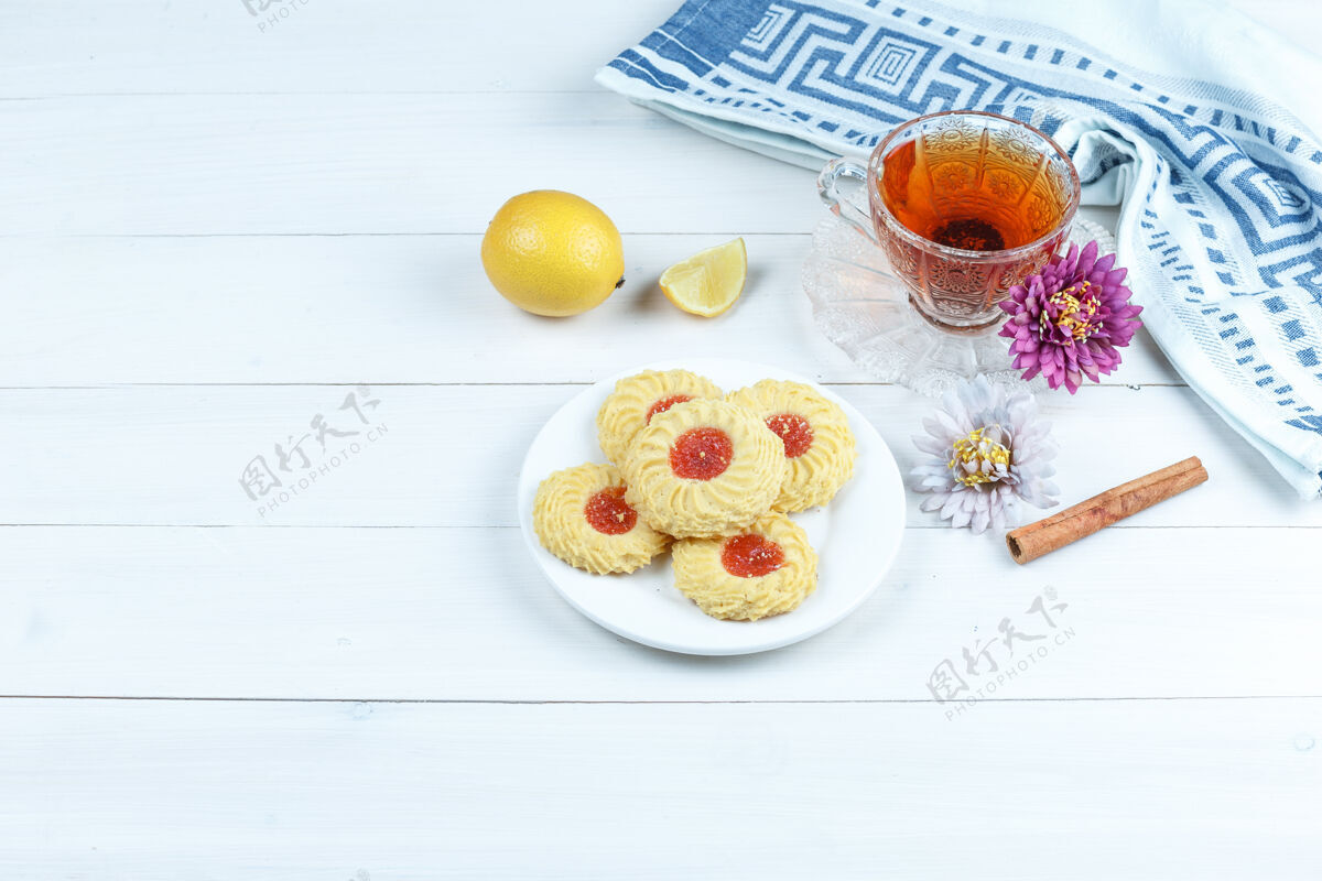 桌子一些饼干 桂花 一杯茶 厨房毛巾 白木板背景上的柠檬 高角度视图阳光杯子新鲜