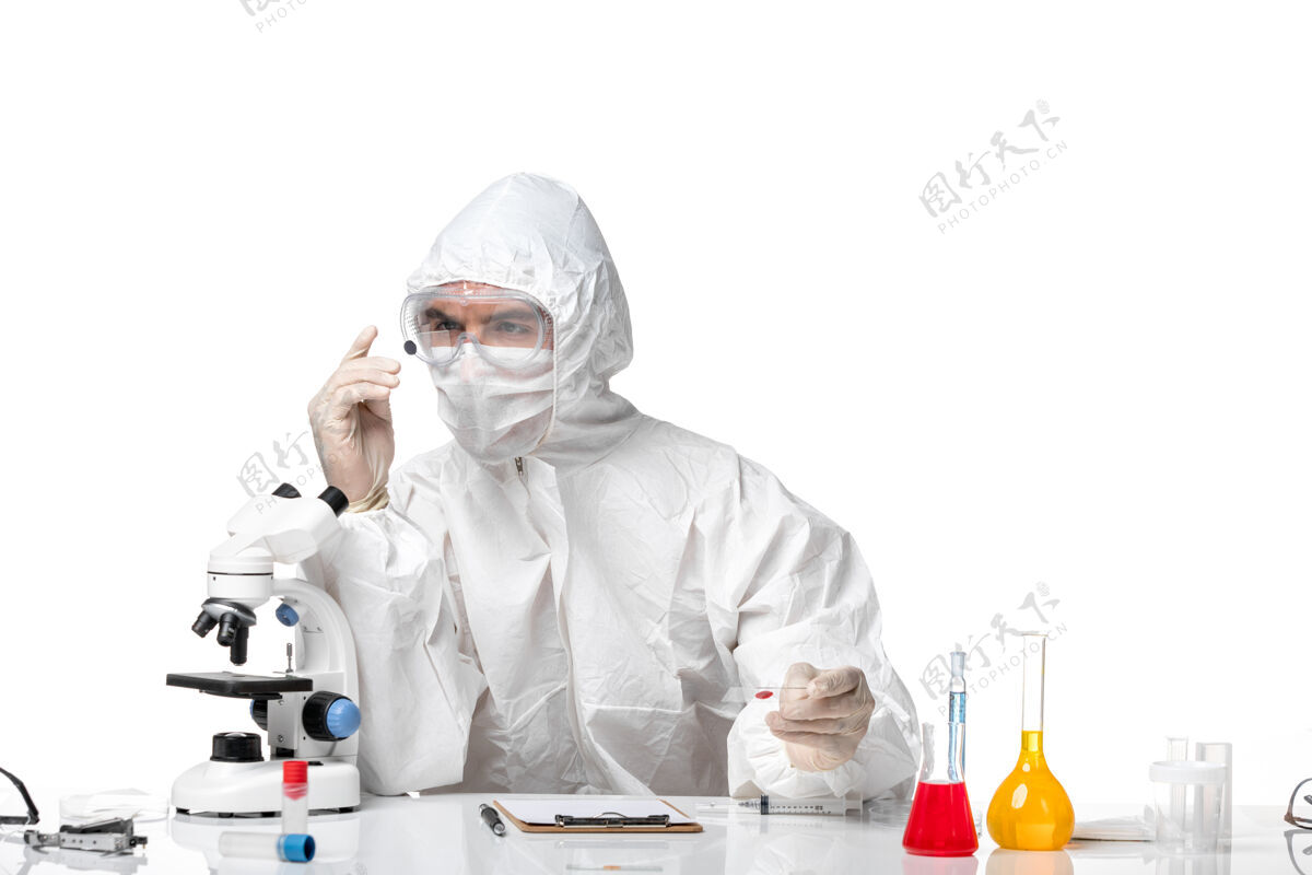 医生正面图：男医生穿着防护服 戴着面罩 因为科维德在白色办公桌上用溶液工作药品防护男医生