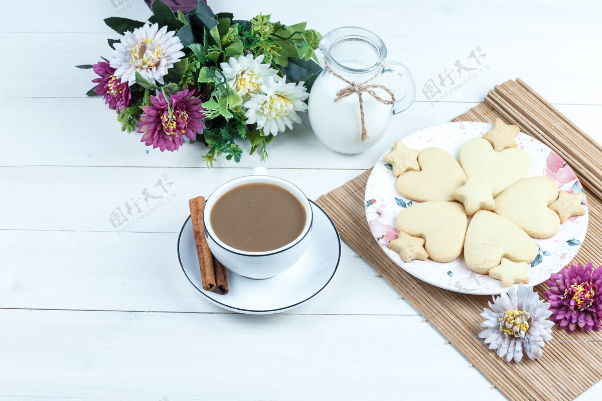 饼干高角度观看心形和星形饼干 鲜花放在放牛奶的垫子上饼干壶零食