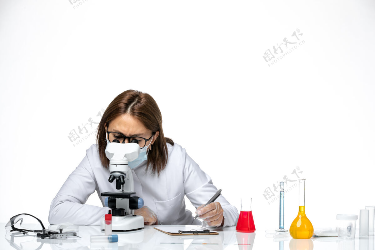 正面前视图：女医生穿着白色医疗服 戴着面罩 在白色空间使用显微镜显微镜电话到期