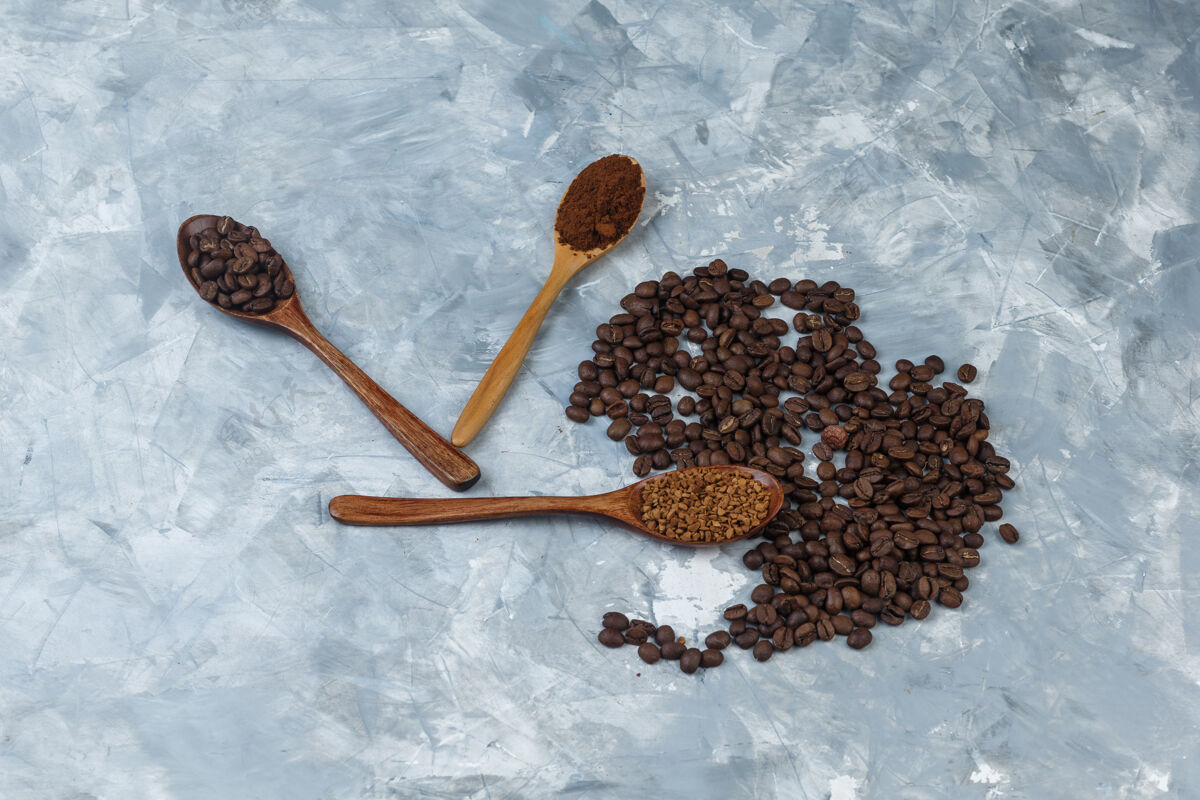 豆子咖啡豆配速溶咖啡 咖啡粉 咖啡豆放在木制勺子里 在浅蓝色大理石背景上特写食物咖啡因大理石