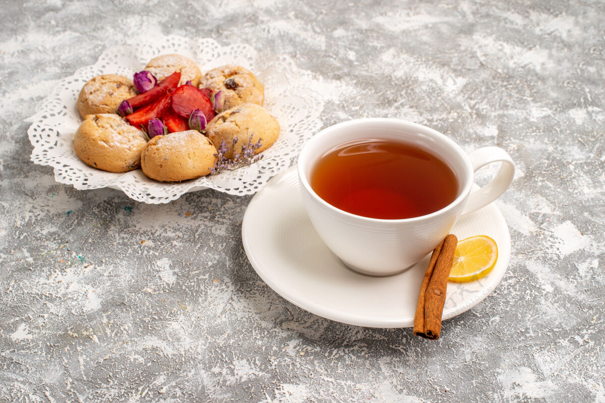 糖正面是美味的沙曲奇和新鲜的草莓和一杯茶在一个白色的空间茶饼干咖啡