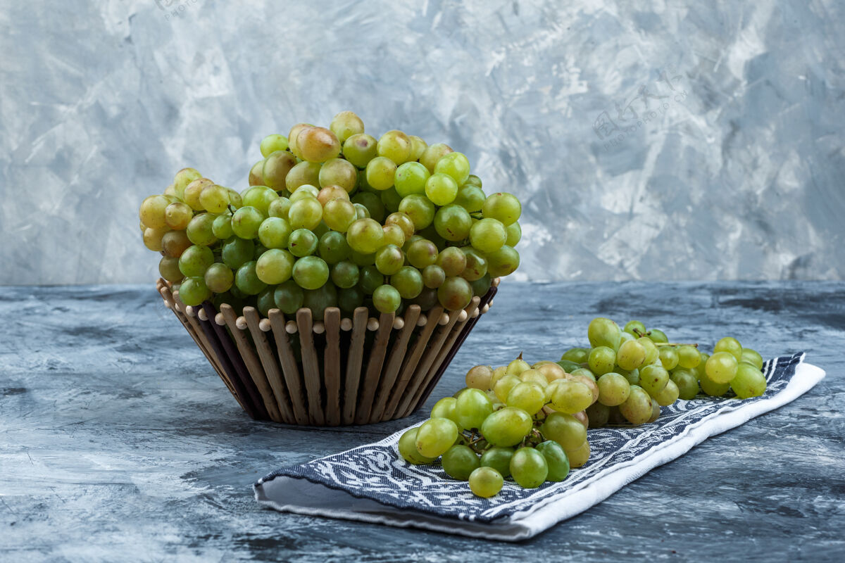 卷须新鲜的葡萄在一个篮子侧视图在肮脏的石膏和厨房毛巾的背景食物秋天小